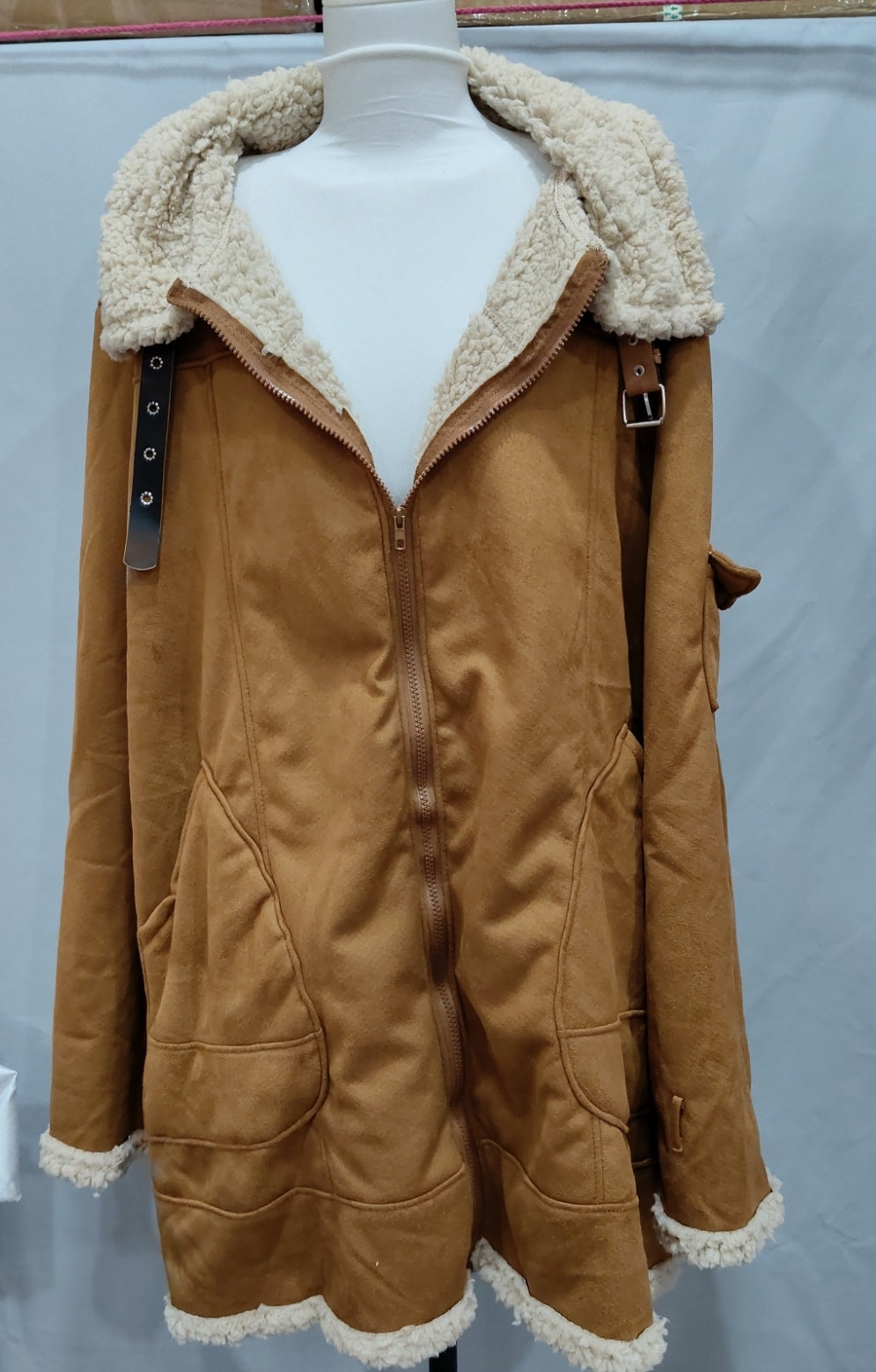 Tan zip-front winter jacket on a mannequin with broad fleece-style collar and front pockets