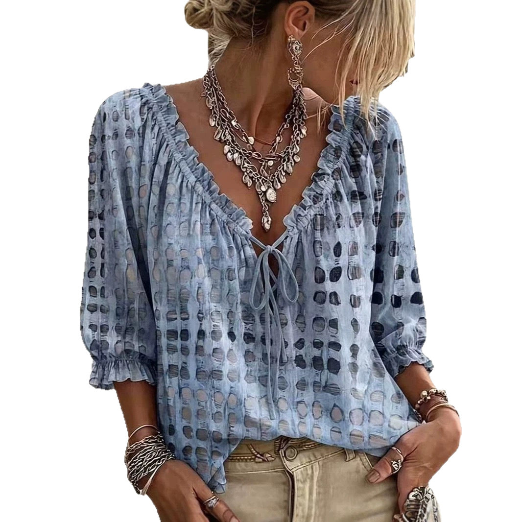 Light blue printed blouse with ruffled neckline and front tie shown on a model