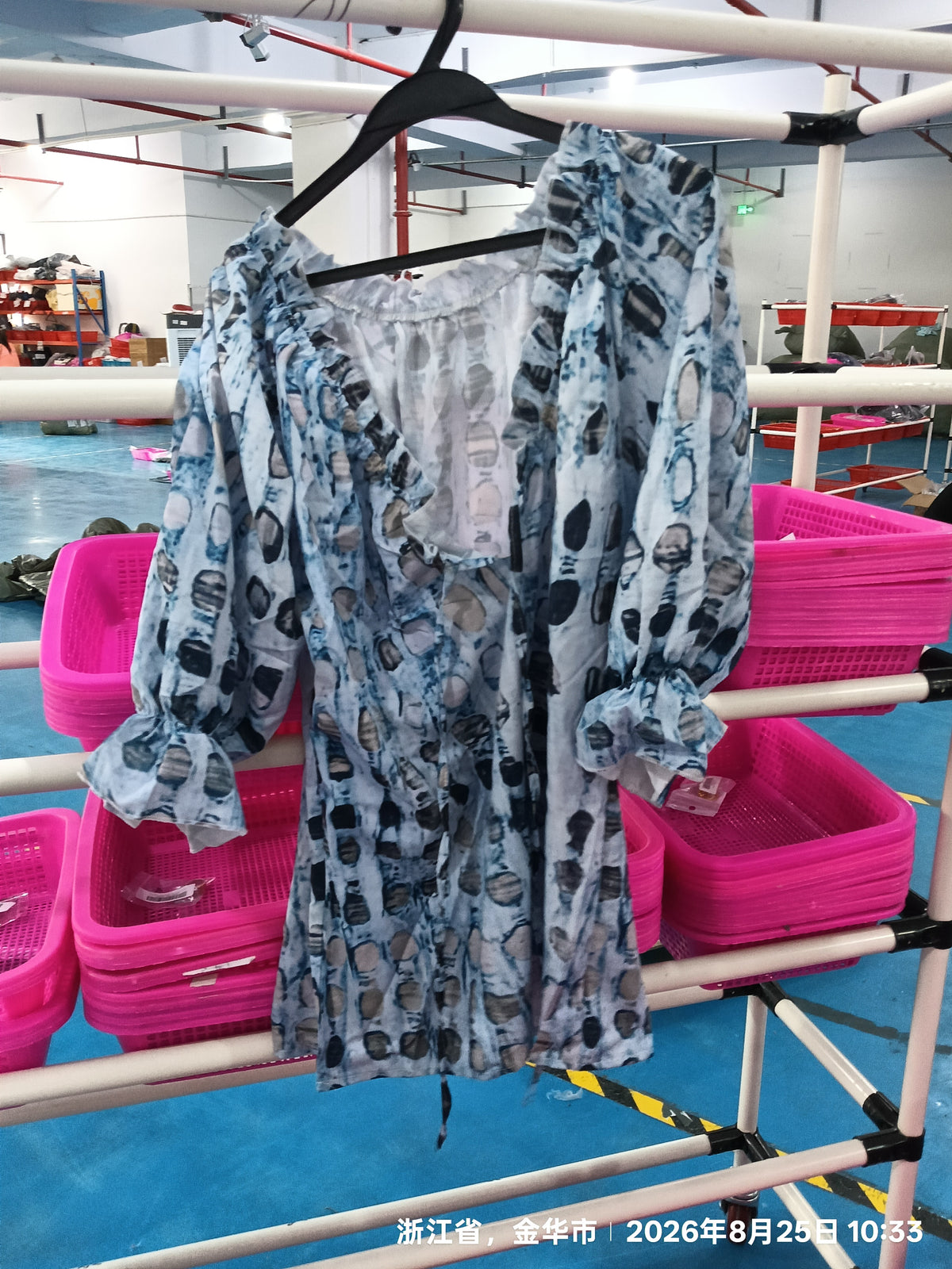 Blue patterned tie-neck blouse hanging on a rack with ruffled sleeves