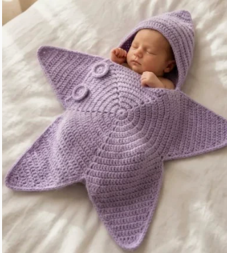 Purple hooded star-shaped crochet outfit with button detailing pictured on a baby