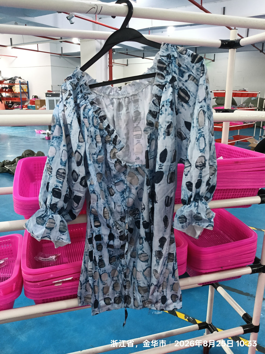 Blue printed blouse on a hanger showing ruffled neckline and gathered sleeves