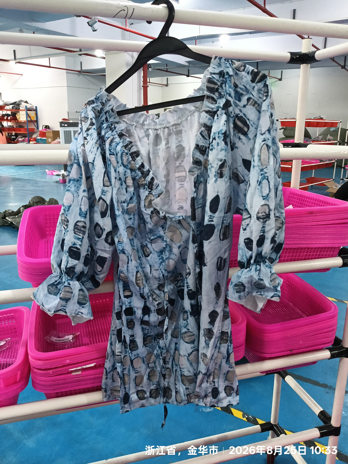 Blue printed blouse on a hanger showing ruffled neckline and gathered sleeves
