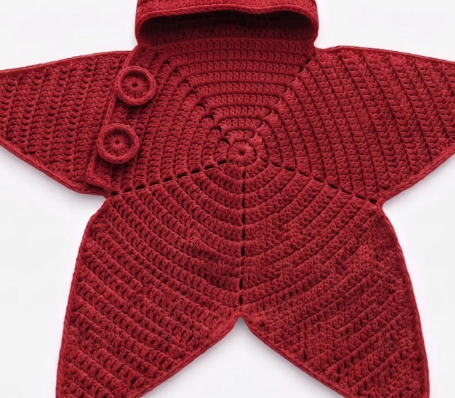 Close-up of red star-shaped crochet outfit showing circular stitching and button detailing