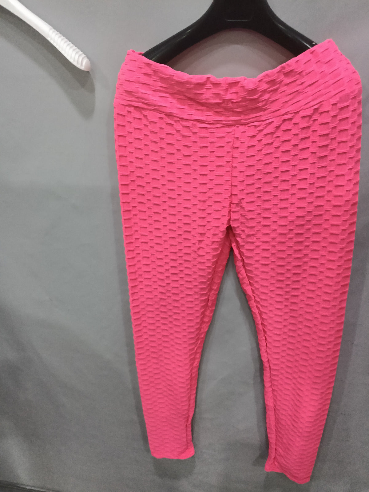 Pink textured leggings hanging from a black hanger