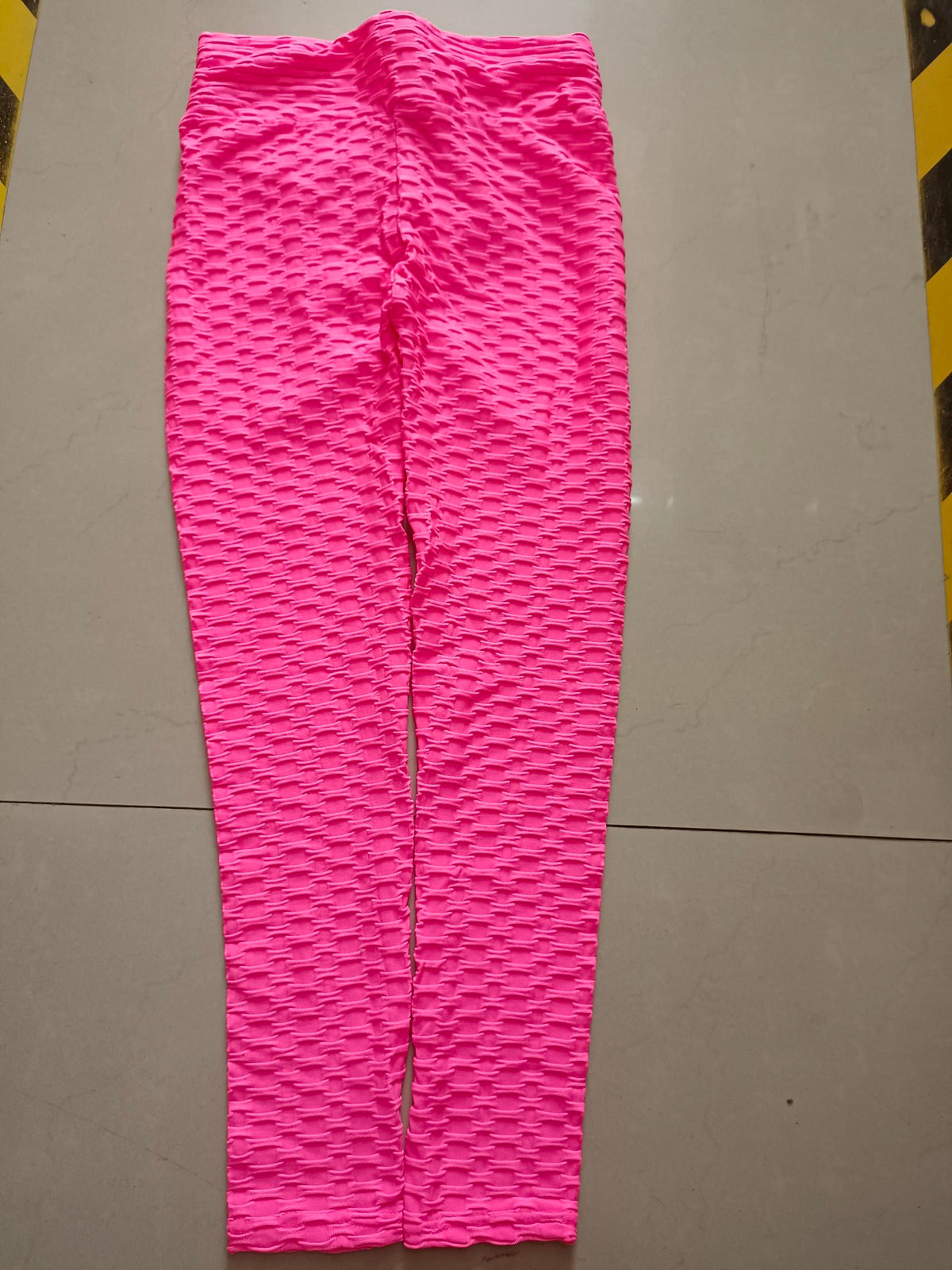 Pink textured scrunch leggings laid flat to show the gathered back seam
