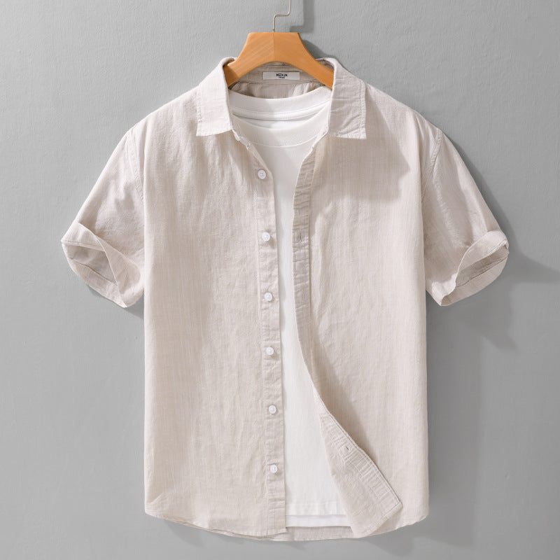 Light khaki short-sleeve button-front shirt on a hanger over a white T-shirt